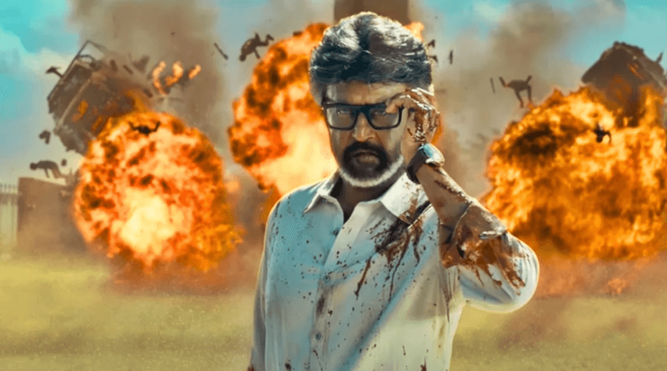 Superstar Rajinikanth adjusting his glasses with blood on his shirt as massive fireball explosions erupt behind him in Jailer 2